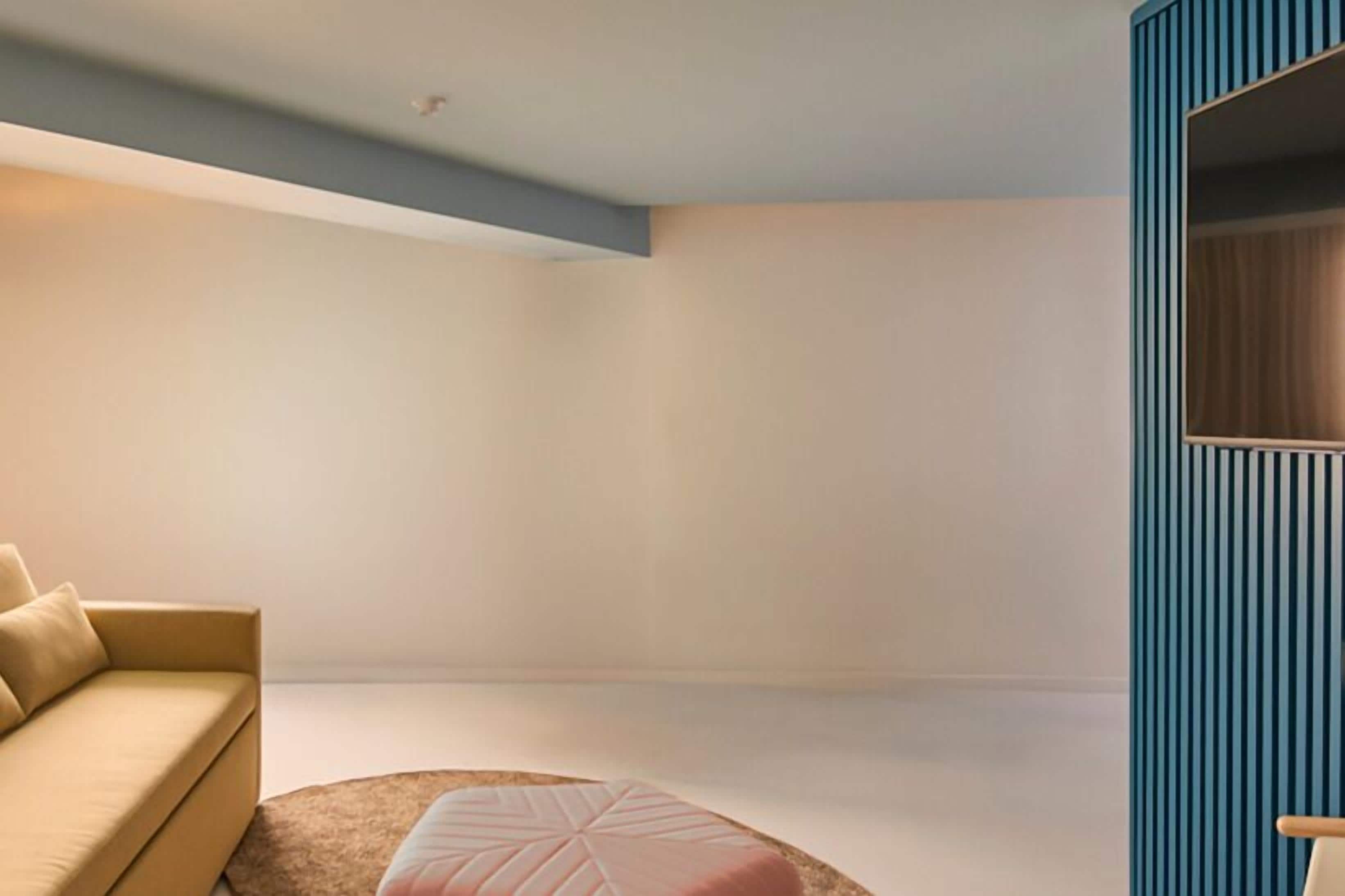 A modern room with a beige sofa, a round ottoman, and a blue accent wall.