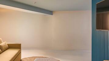 A modern room with a beige sofa, a round ottoman, and a blue accent wall.