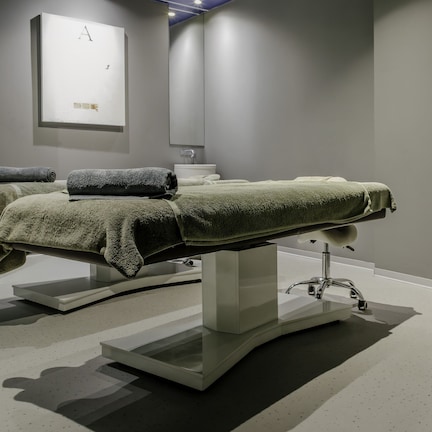 A modern bathroom with a large sink, two towel-wrapped massage tables, and a minimalist design.