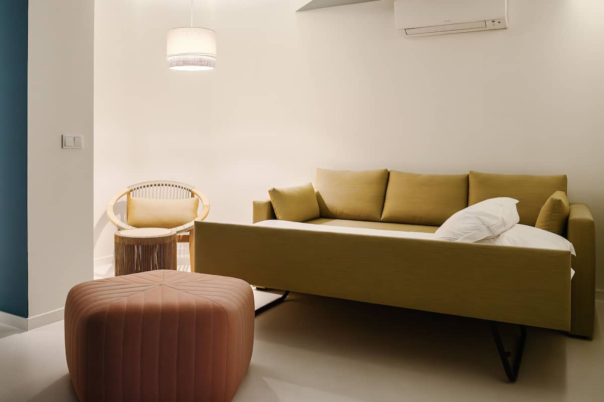 A modern living room with a sofa, a chair, and a small ottoman.