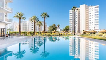 Een buitenzwembad, parasols bij het zwembad en ligstoelen