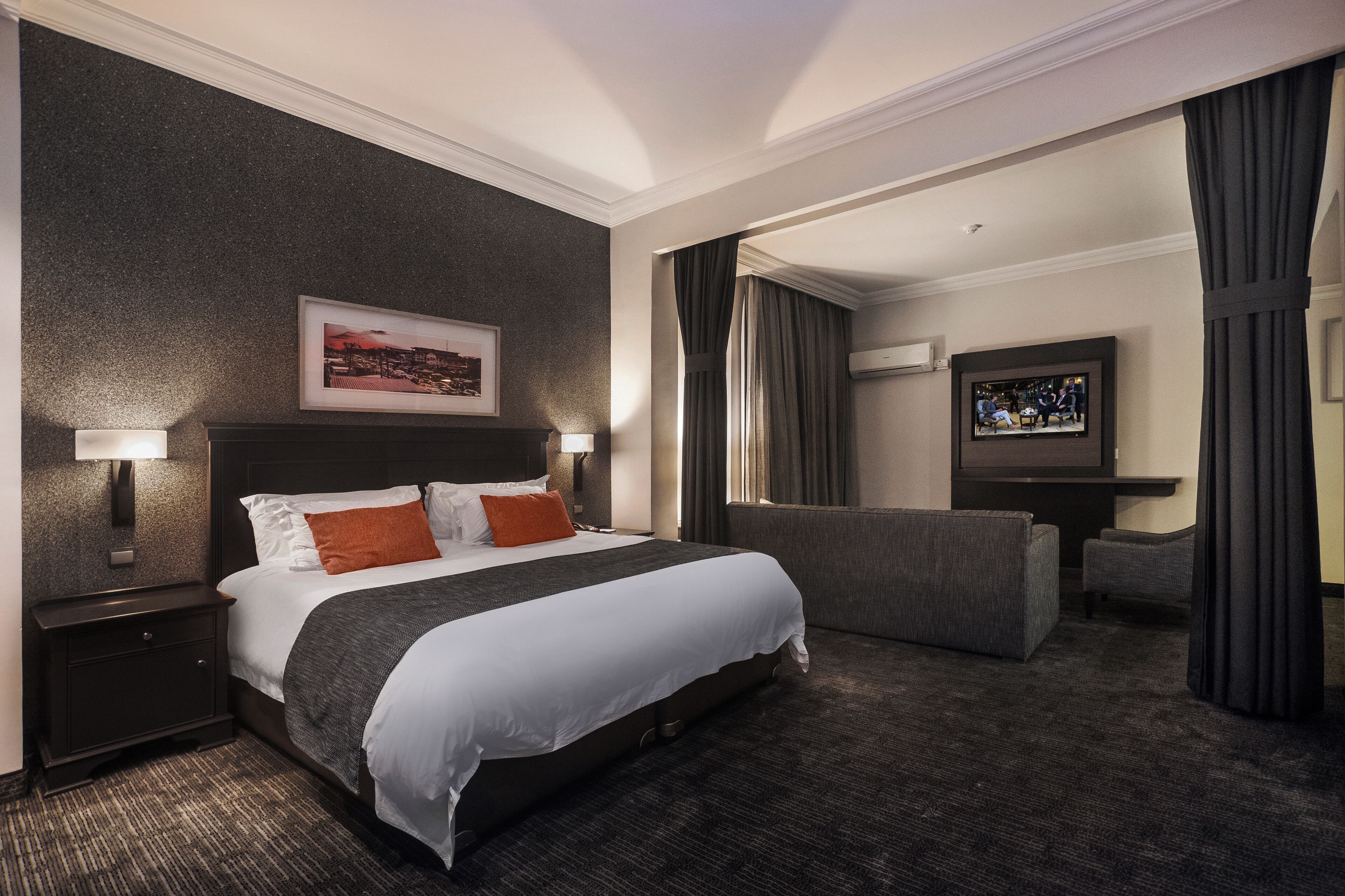Ein Hotelzimmer mit einem großen Bett, einem Fernseher, einer Couch und einem gerahmten Bild an der Wand.