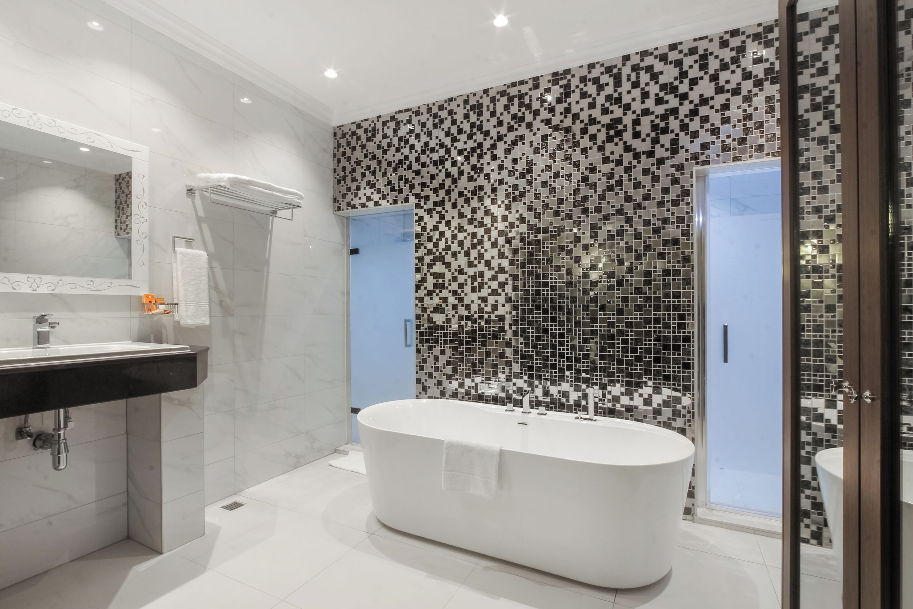 A modern bathroom with a freestanding bathtub, a large mirror, and a tiled shower area.
