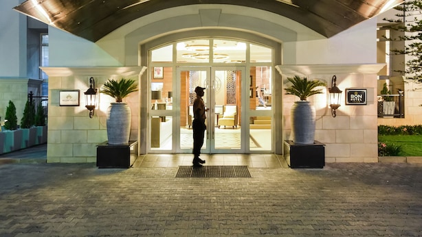 A hotel entrance with a covered entrance, large potted plants, and a sign indicating the hotel name. - BON Hotel Abuja (Abuja)