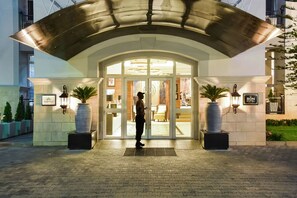 A hotel entrance with a covered entrance, large potted plants, and a sign indicating the hotel name. - BON Hotel Abuja (Abuja)