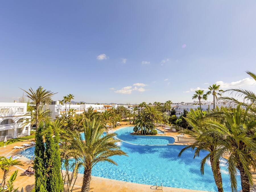 Una gran piscina rodeada de palmeras y edificios blancos.