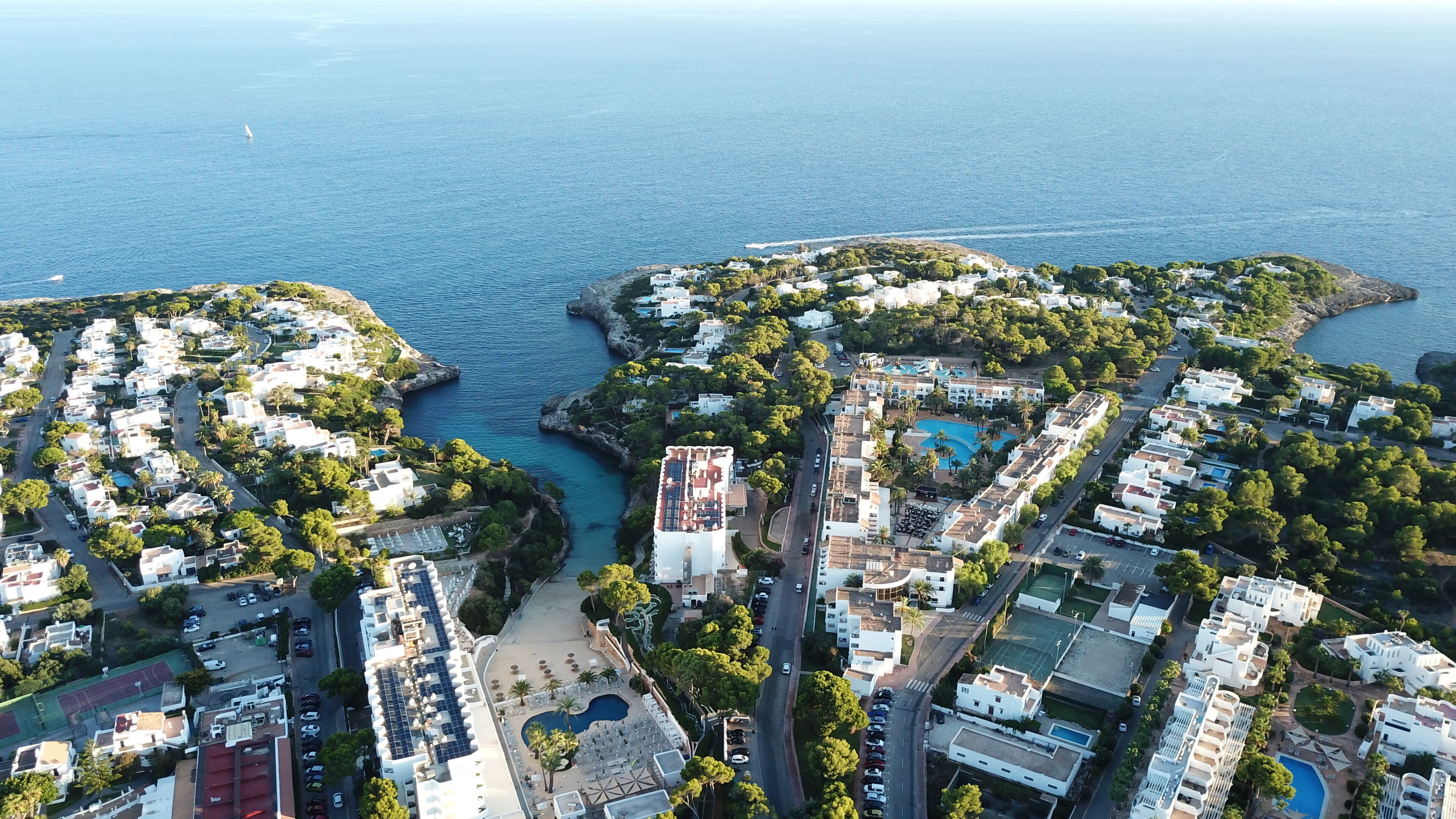 Vista aérea de una zona residencial costera con edificios, carreteras y un puerto deportivo.
