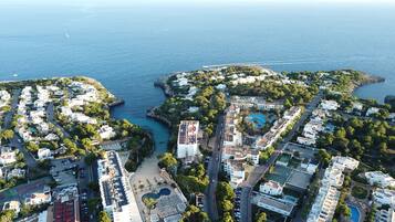 Vista aérea de una zona residencial costera con edificios, carreteras y un puerto deportivo.
