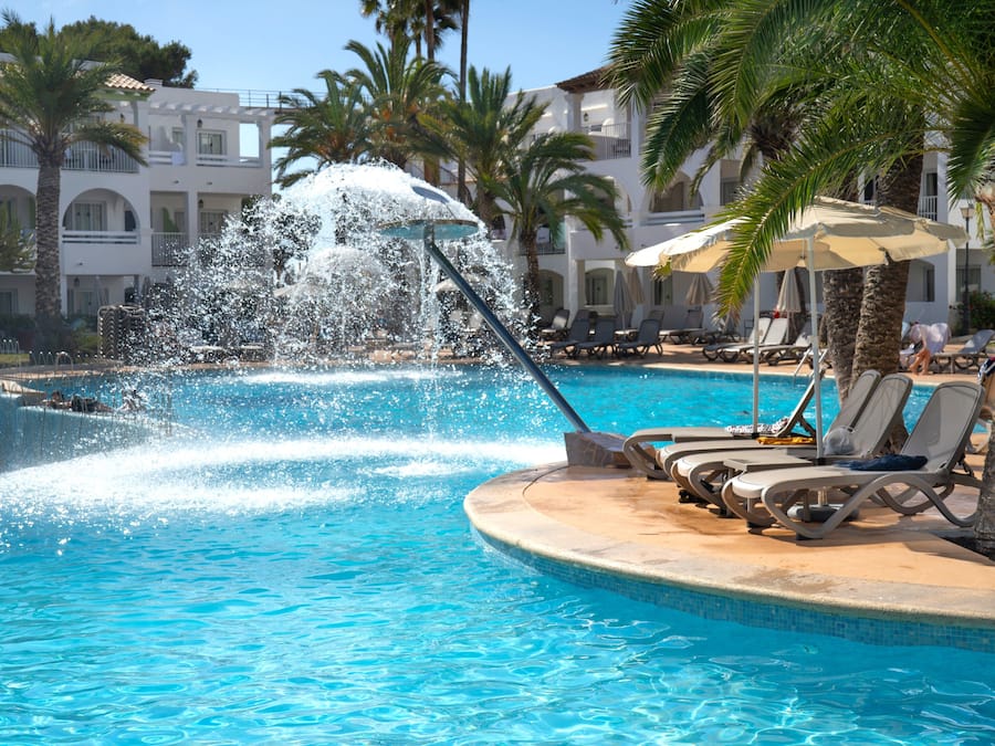 Una piscina al aire libre, sombrillas, sillones reclinables de piscina