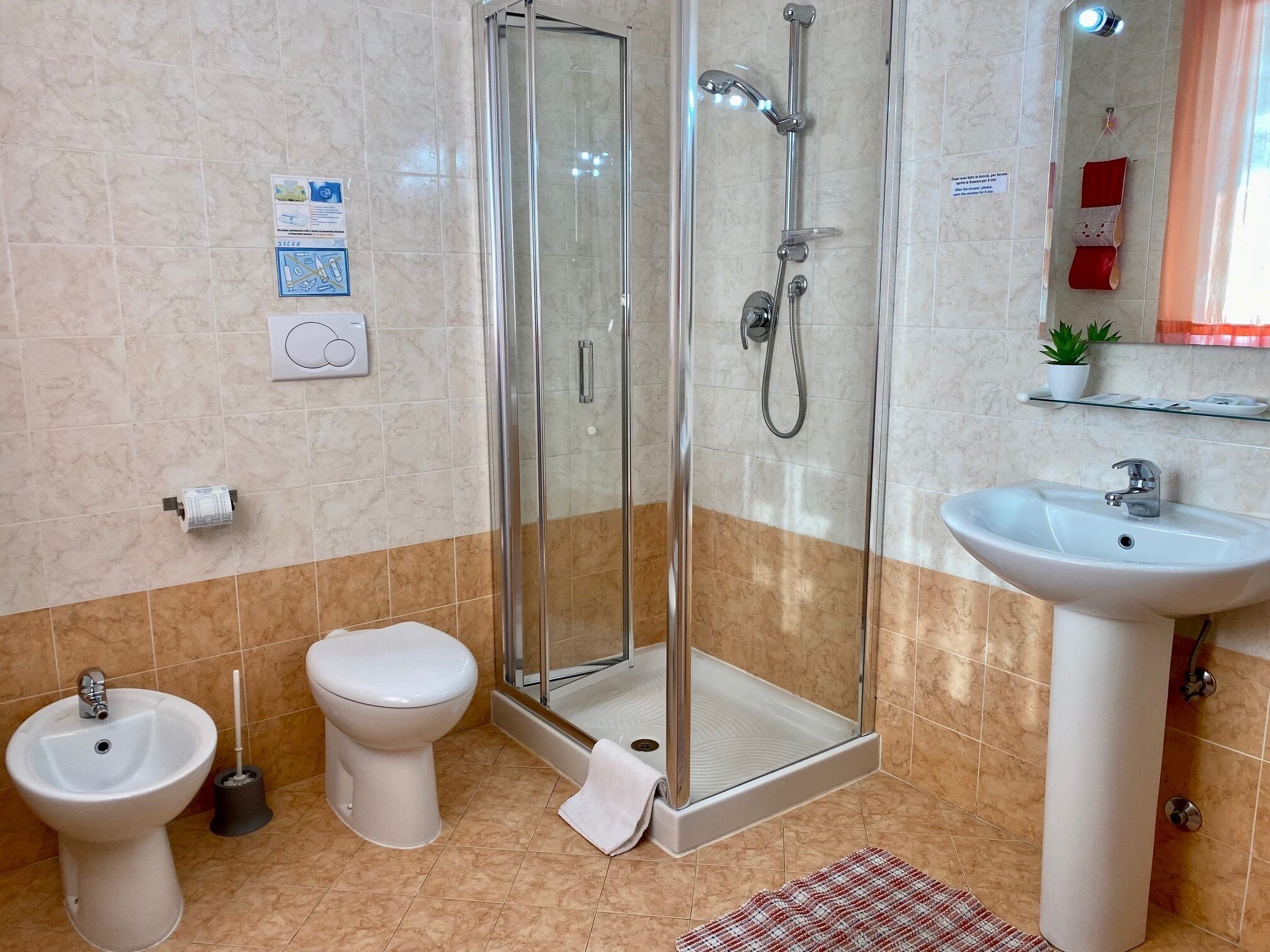 Un baño con ducha de vidrio, lavamanos, inodoro y bidé.