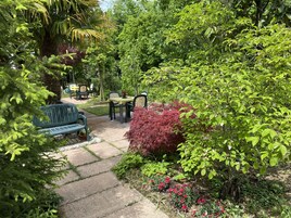 Un patio giardino con una panchina, tavoli e sedie.