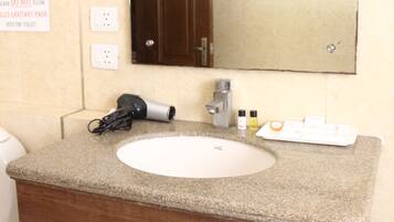 Une salle de bain équipée d’un lavabo, d’un miroir et d’une pancarte indiquant qu’il est interdit de jeter les protections hygiéniques dans les toilettes.