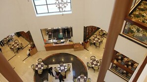 Eine Hotelhalle mit einer zentralen Rezeption, mehreren Sitzbereichen und einer dekorativen Deckenkonstruktion.