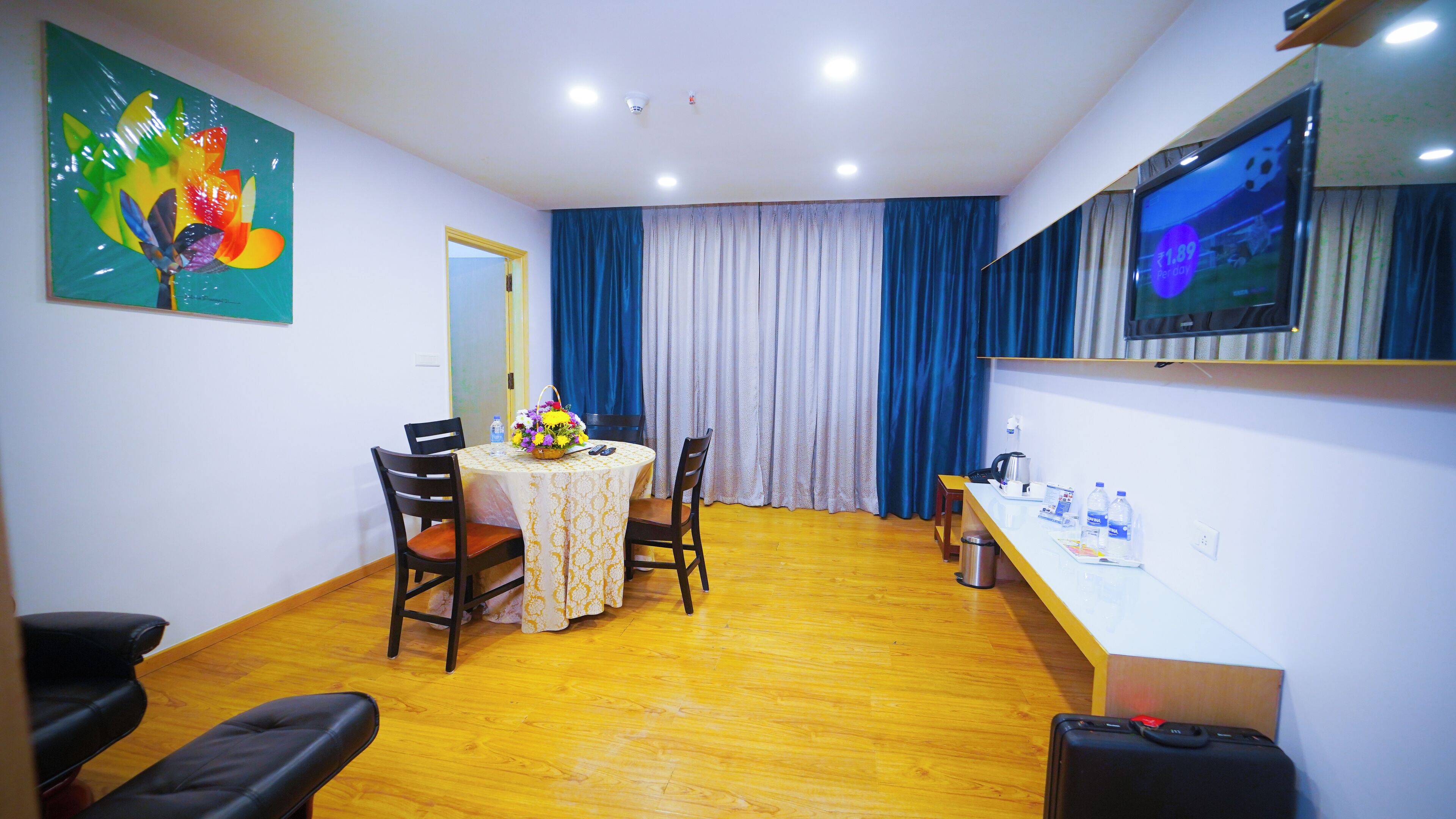 A hotel room with a dining area, a TV, and a bed.