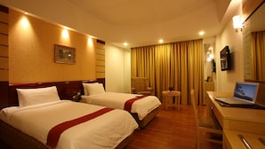 Ein Hotelzimmer mit zwei Betten, einem Schreibtisch mit einem Laptop, einem Stuhl und einem kleinen Tisch.