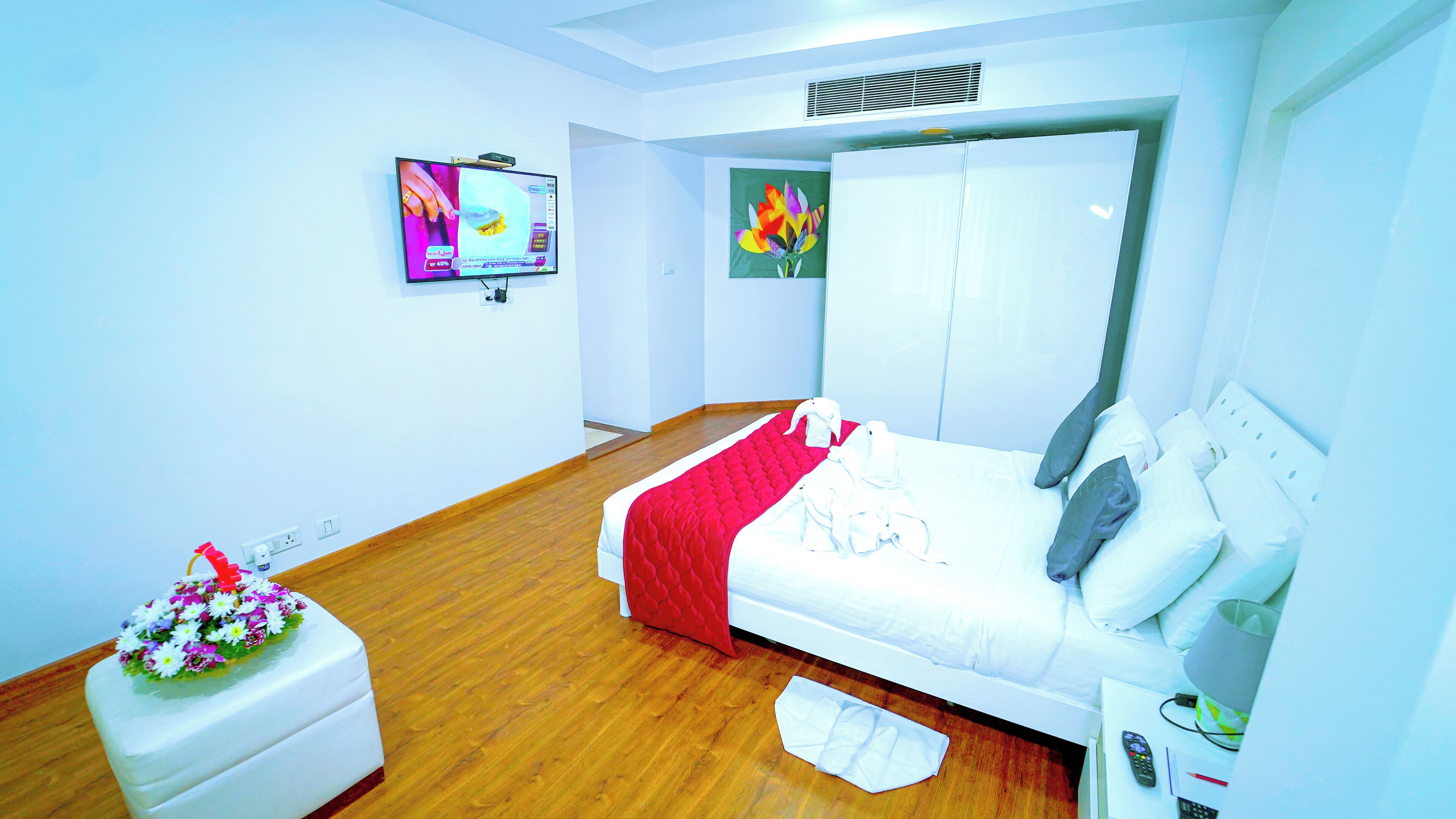 Habitación de hotel con cama, televisor, armario y una pequeña mesa con control remoto.