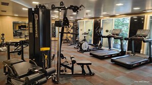 Ein Fitnessstudio mit verschiedenen Trainingsgeräten, darunter Laufbänder, ein Ergometer und Kraftgeräte.