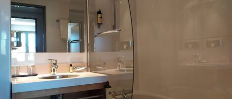 A modern bathroom with a glass-enclosed shower, a double sink vanity, and a bathtub.