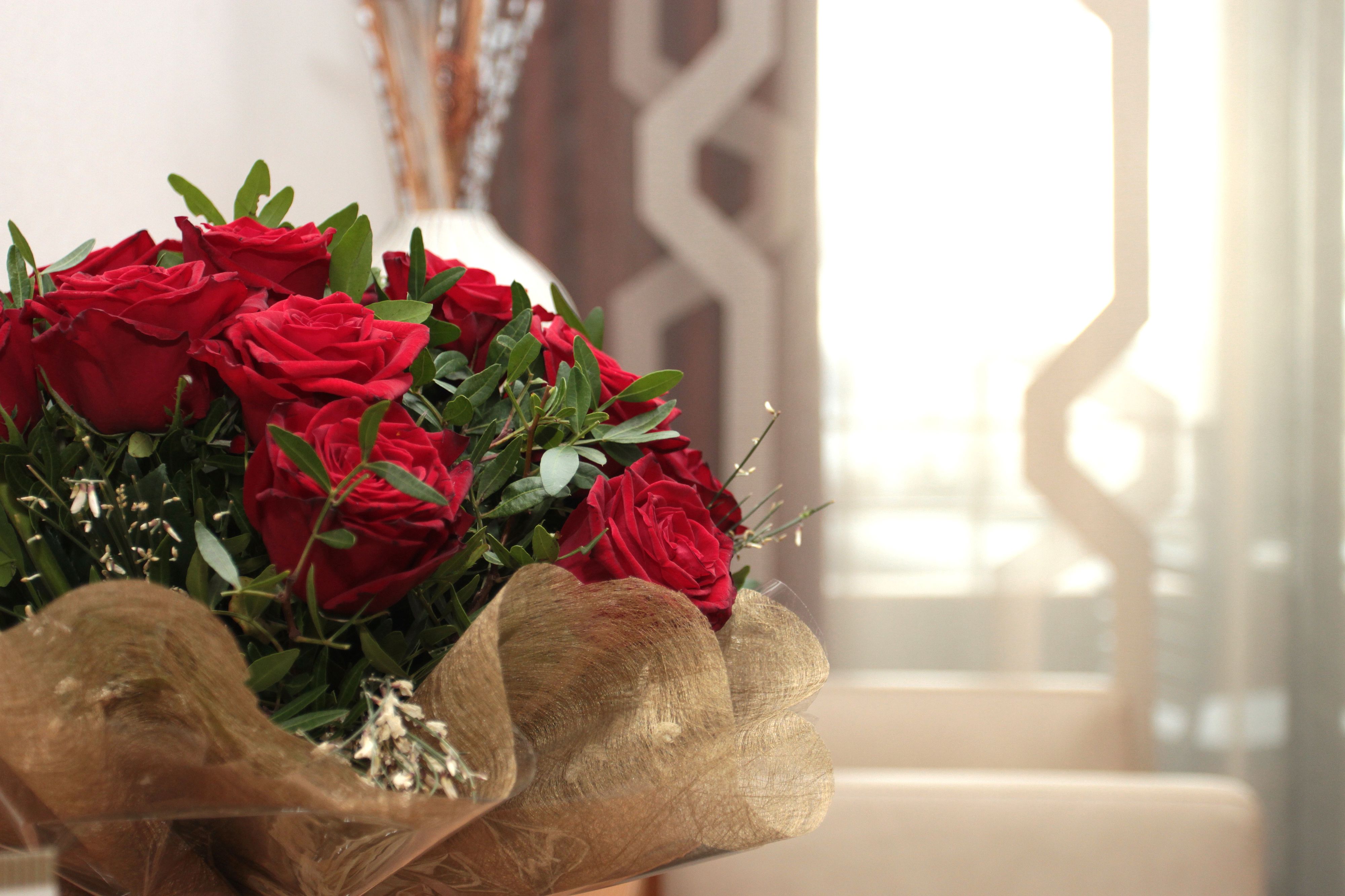 A bouquet of red roses in a clear vase with a golden wrapping.