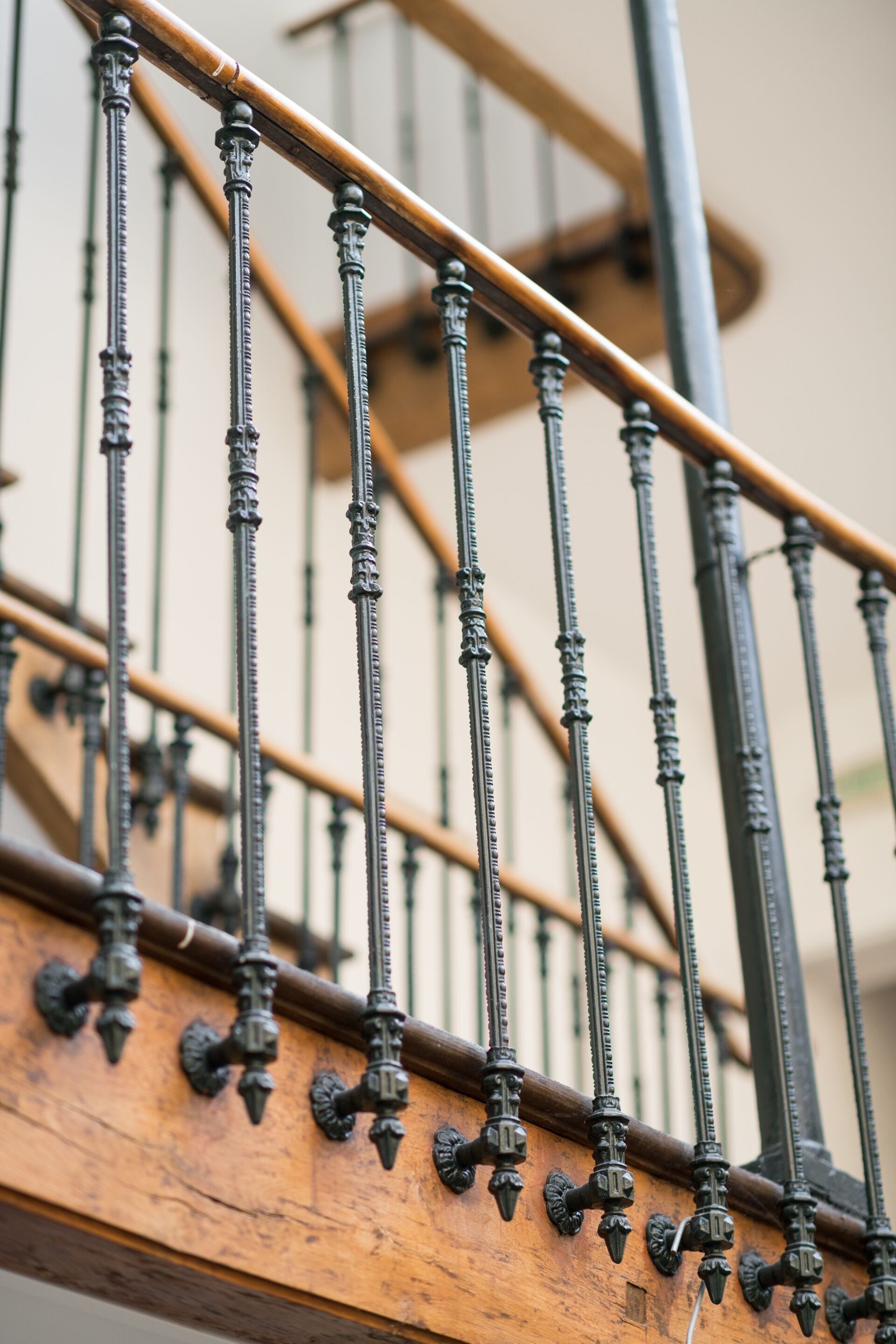 A close-up of a wooden staircase with ornate metal balusters and a handrail.