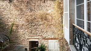 A stone wall, a window with white shutters, a metal railing, and a small fountain. - Hôtel des Tonneliers  (Beaune)