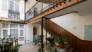 A multi-level interior with a wooden staircase, potted plants, and a map on the wall. - Hôtel des Tonneliers  (Beaune)