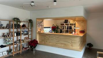 A modern interior with a wooden reception desk, shelves with various items, and a speckled floor.
