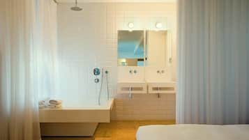 A modern bathroom with a bathtub, two sinks, and a shower.