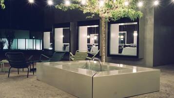 Zona de piscina interior moderna amb envàs de vidre, seients i llums penjants.