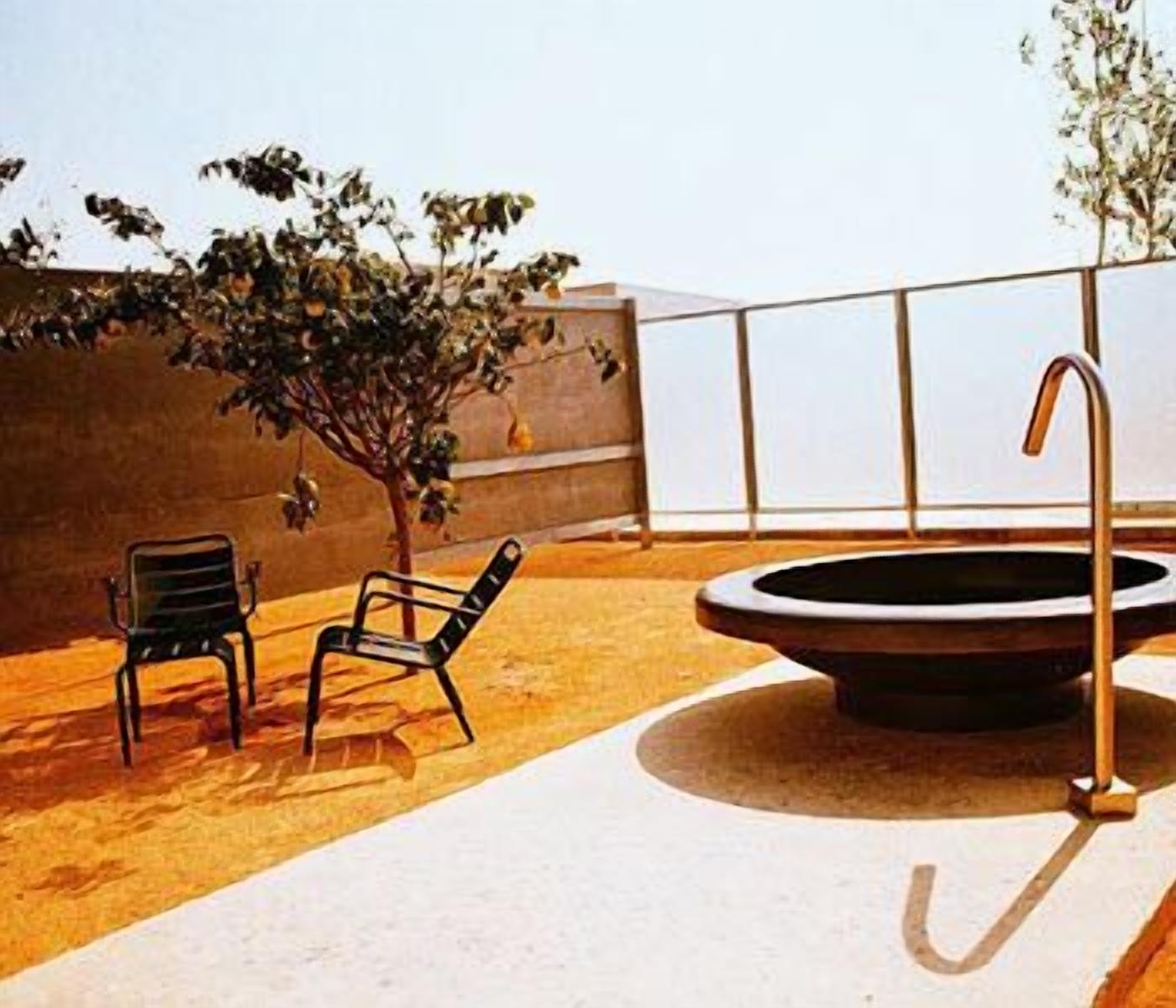 Un área de estar al aire libre con dos sillas, una mesa redonda y una fuente de agua.