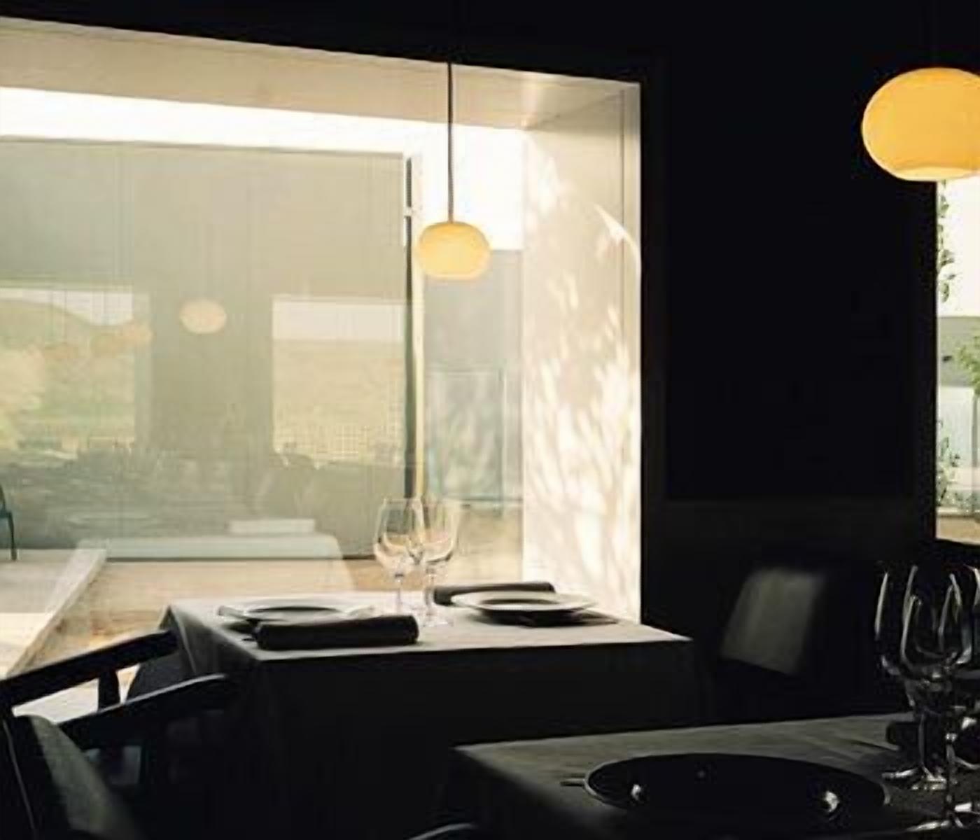 A dining area with a table set for two, a wine glass, and a pendant light.