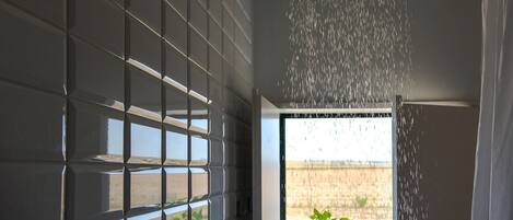 A room with a large window, a view of a field, and a water feature.
