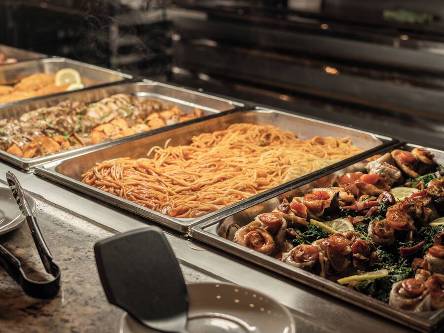 A buffet with various dishes including pasta, seafood, and salads.