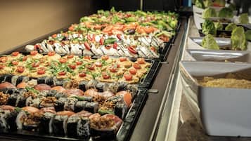 Un bufé con diversas opciones de comida, incluyendo sushi, ensaladas y otros platos.