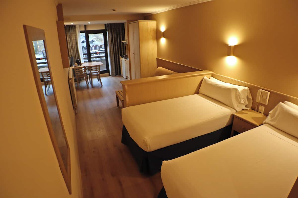 A hotel room with two beds, a desk, and a chair.