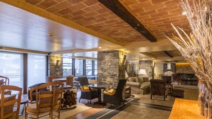 Amplia sala de estar con una pared de acento de piedra, muebles de madera y ventanas grandes que dejan entrar luz natural.
