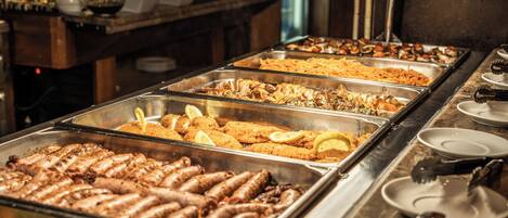 A buffet with various food options including meats, pasta, and salads.