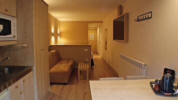 A compact hotel room with a kitchenette, a sofa, a dining table, and a small coffee table.