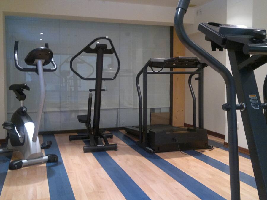 Un gimnasio con equipo de ejercicio, incluyendo una bicicleta estática, una elíptica y una cinta de correr.