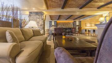 Una sala de estar acogedora con una chimenea de piedra, un sofá grande y una mesa de centro.
