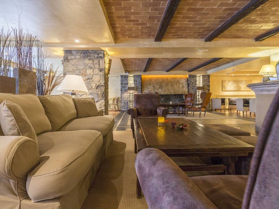 Una sala de estar acogedora con una chimenea de piedra, un sofá grande y una mesa de centro.
