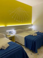 Habitación de hotel con dos camas, una mesita de noche con teléfono y un reloj de pared.