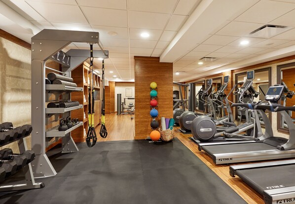A gym with treadmills, ellipticals, and free weights.