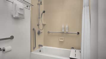 Un baño con bañera, ducha, toallero, pasamanos y dos botellas de champú.