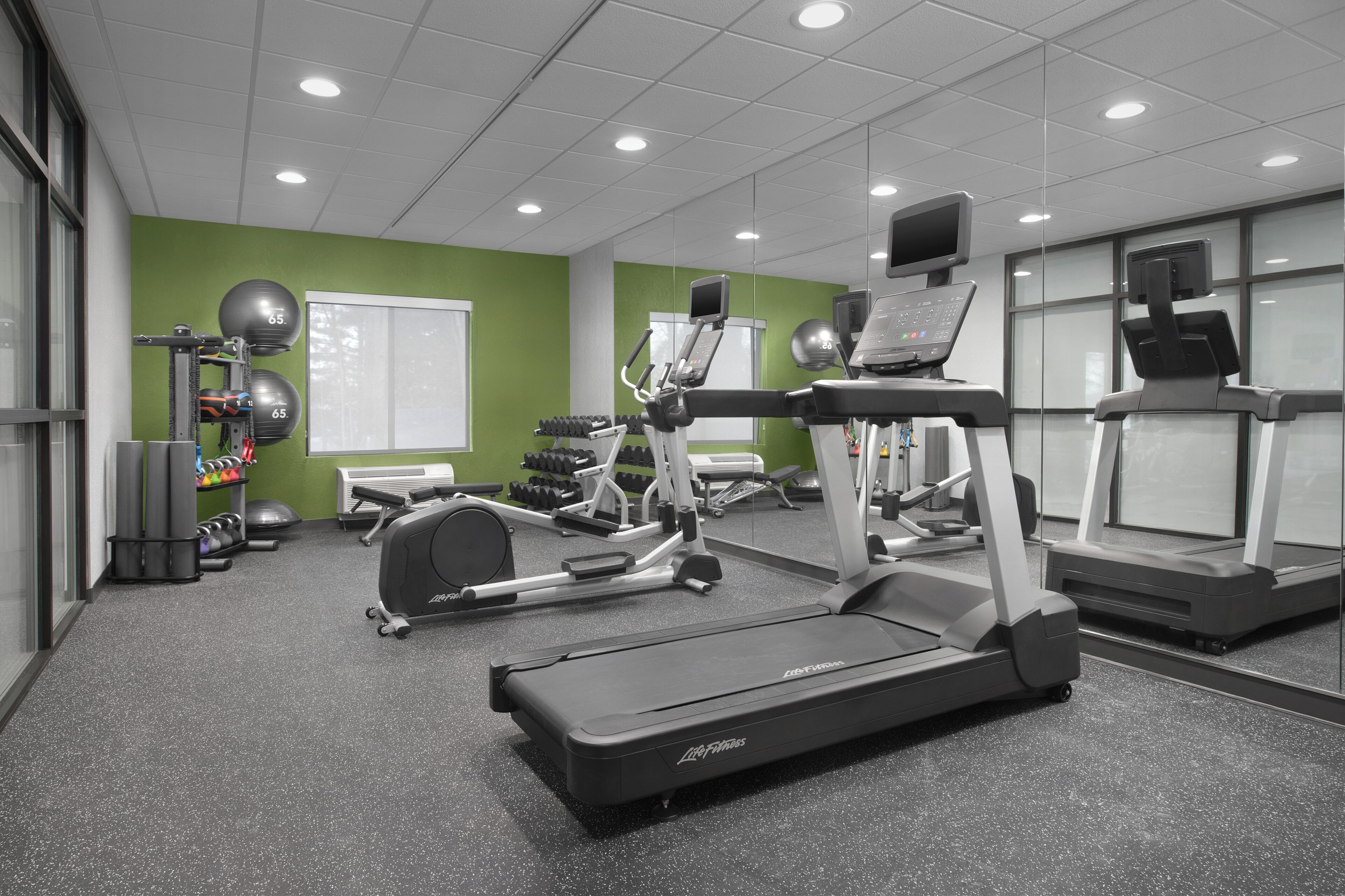 Ein Fitnessraum mit Laufbändern, Gewichten und Trainingsbällen.