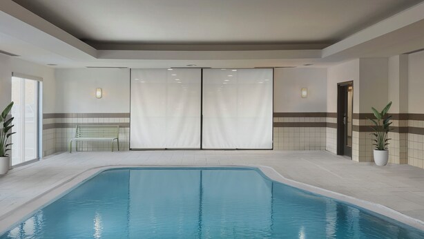 Una piscina interior con un banco, una puerta y plantas en macetas.