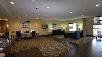 Eine geräumige Lobby mit Empfangsschalter, Computern, einer Sitzecke und großen Fenstern.