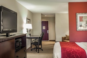 A hotel room with a bed, a desk with a chair, a television, and a microwave.