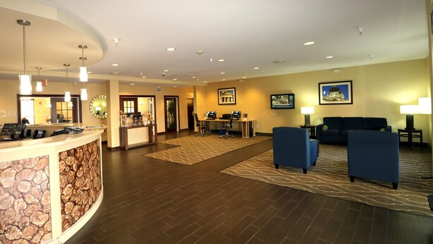 A hotel lobby with a reception desk, seating area, and a dining table.
