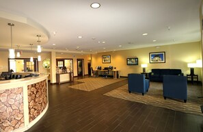 Eine Hotelhalle mit Empfangsbereich, Sitzgelegenheiten und einem Esstisch.